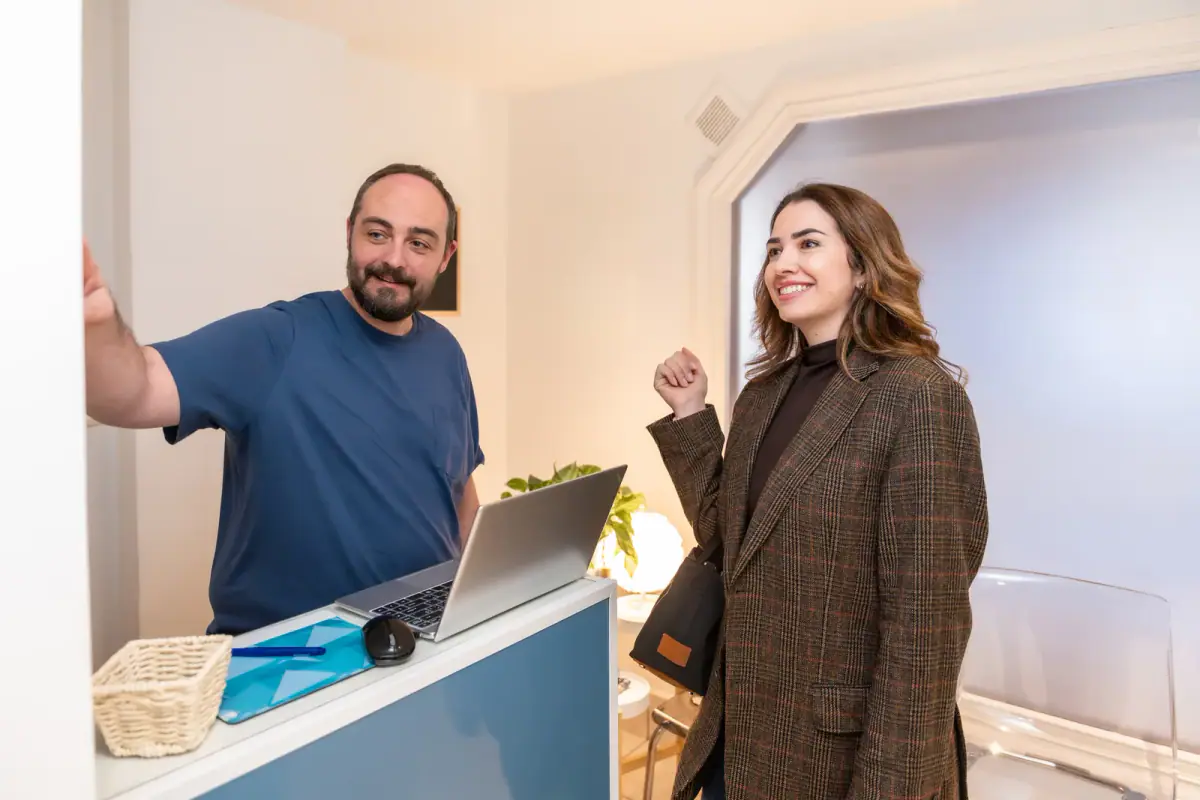 Masseuse welcoming a young woman at a clinic reception, a setting for a part time chiropractic satellite location