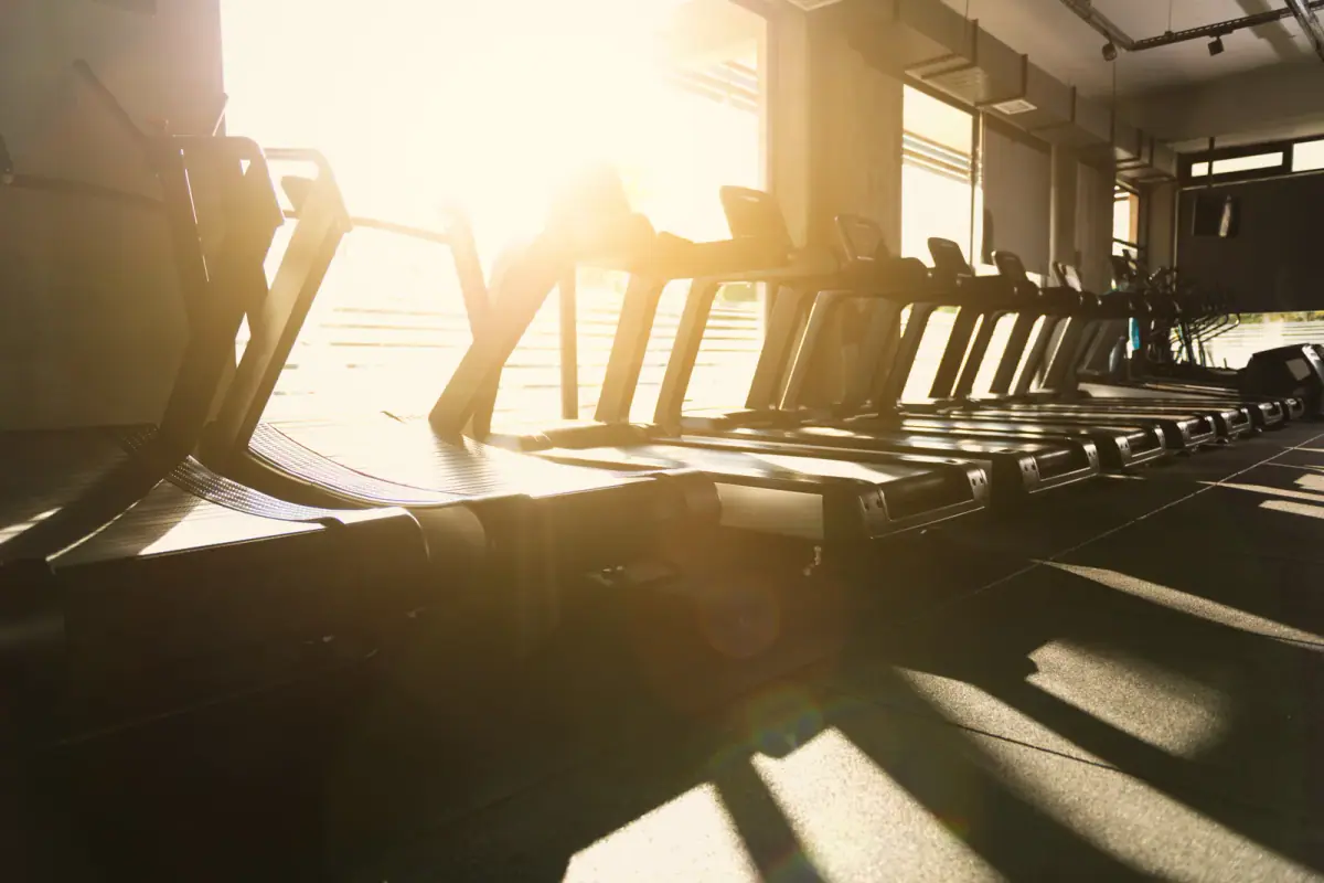 Sunset backlit treadmills in a gym, a view of the quieter hours when peak vs off peak scheduling matters