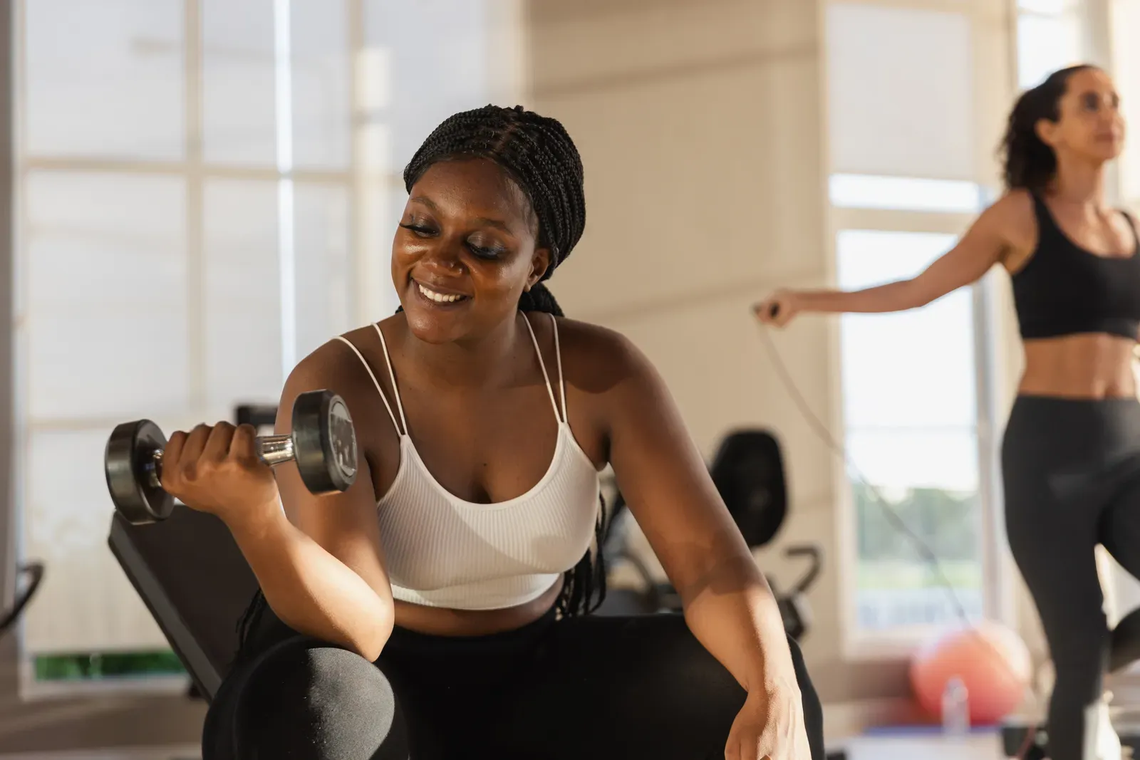 Plus size woman exercising with dumbbells in a bright room