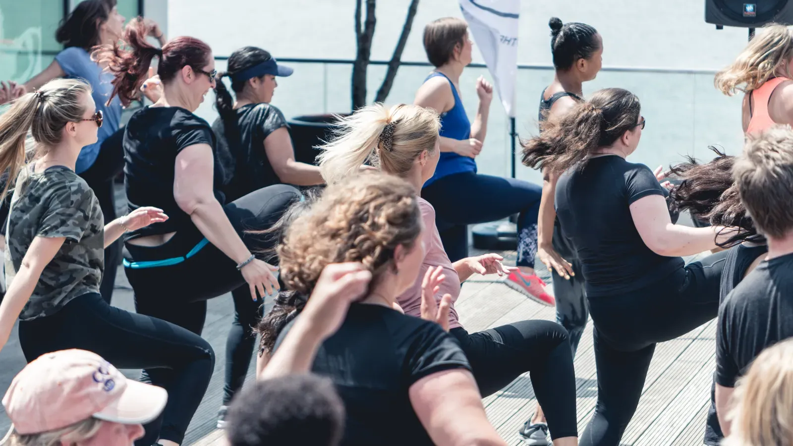 Instructor leading an energetic outdoor group fitness session in the sun