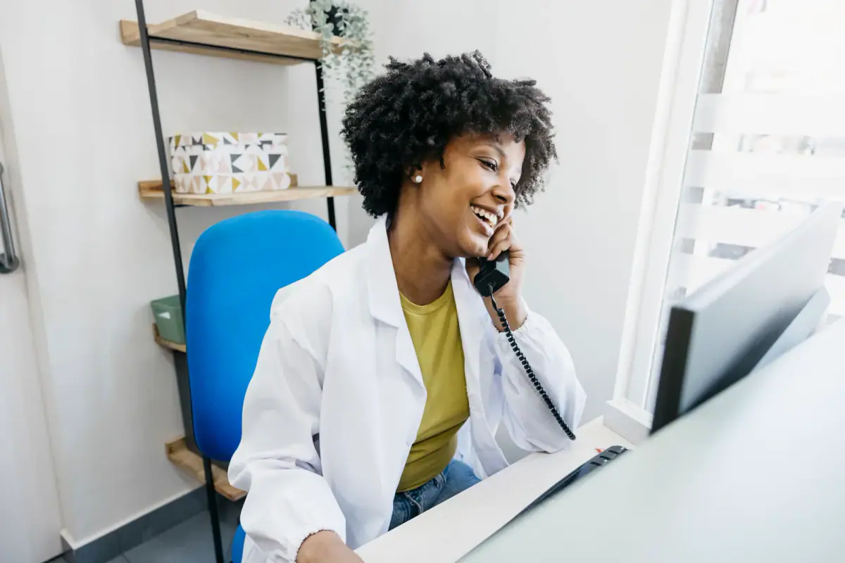 Friendly receptionist managing appointments in a bright clinic, a setting where a practice address on a license may come up