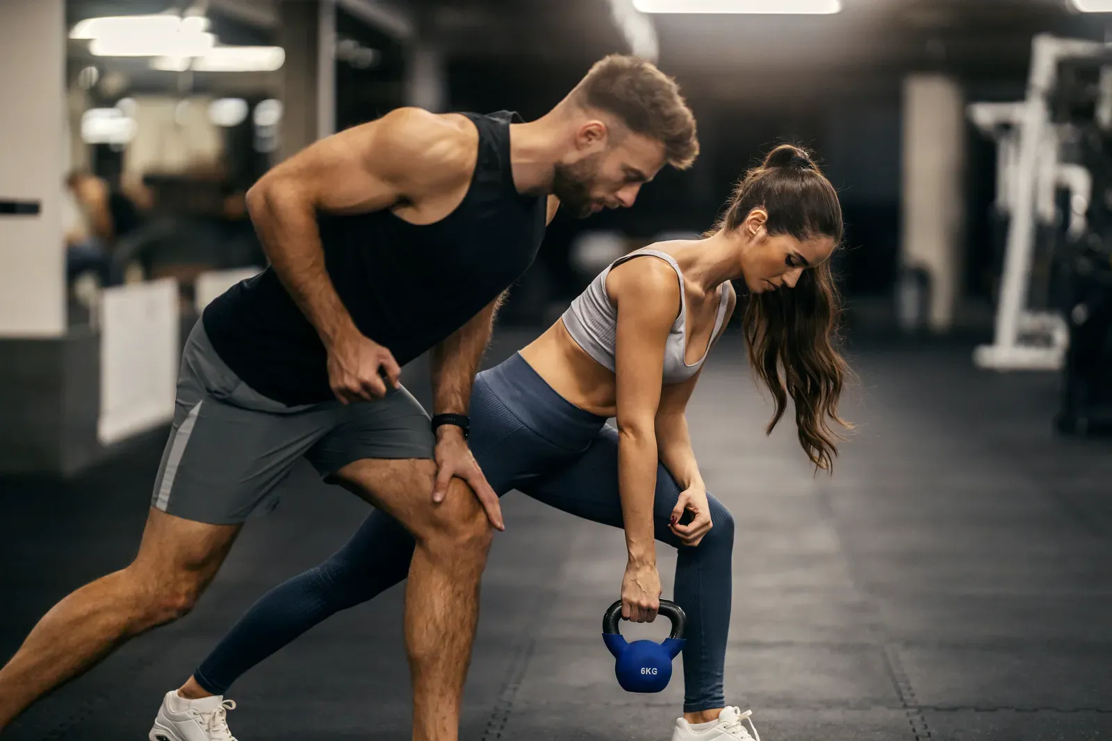 Personal trainer coaching a client through a dumbbell exercise