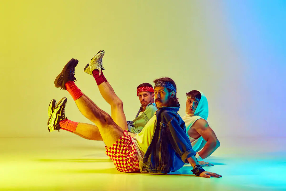 Three young men in vintage sportswear doing aerobics against a yellow and blue background, a fun scene for a private fitness party
