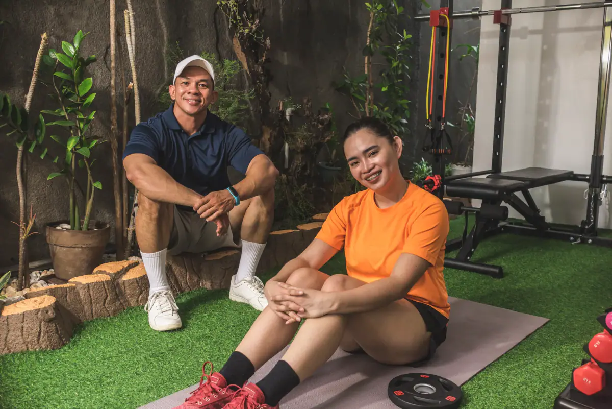 A happy personal trainer and a client in an indoor garden converted into a home gym, a private alternative to a gym floor