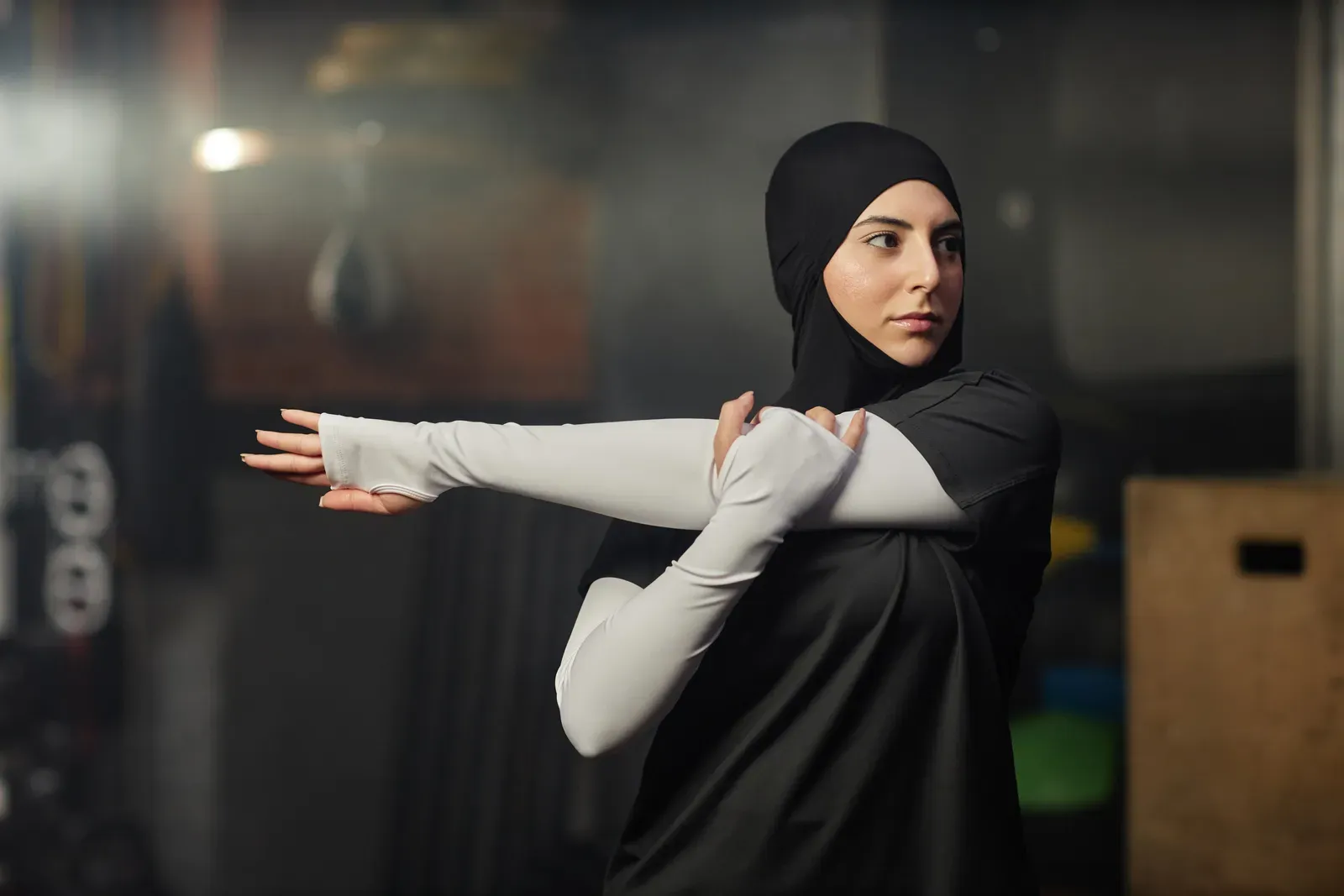 Woman in modest activewear stretching in a calm, private room