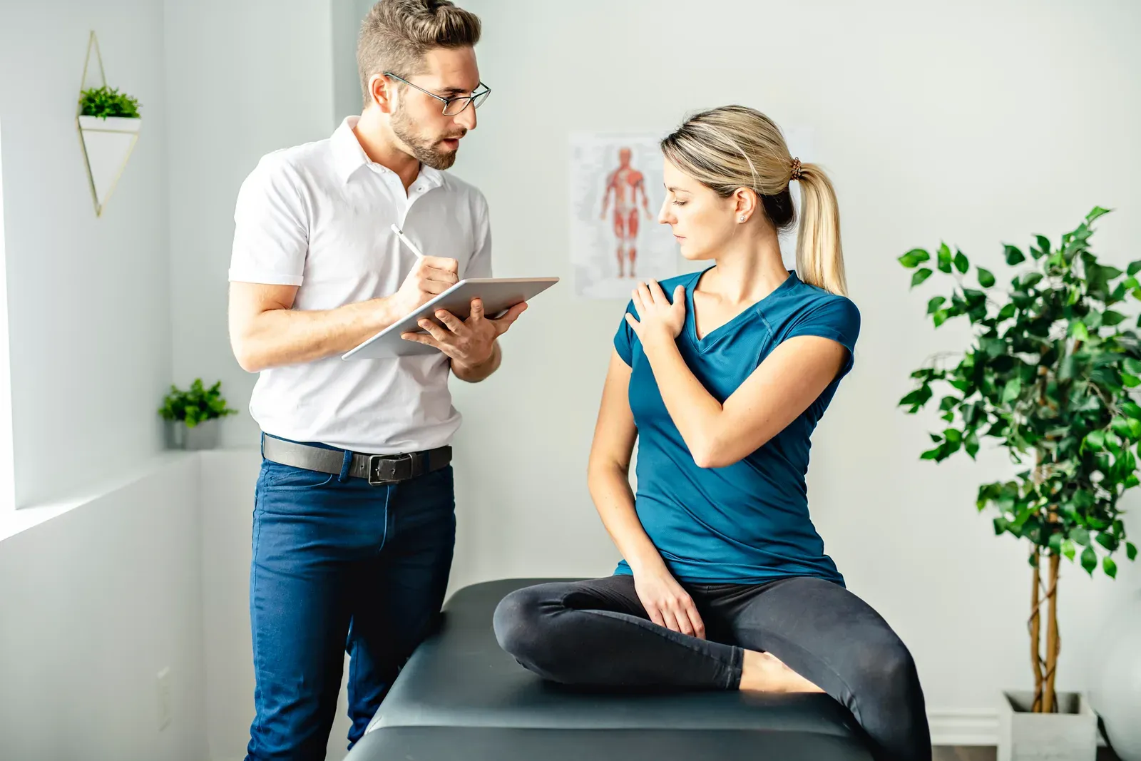 Physical therapist assessing a client's shoulder in a modern rehab clinic