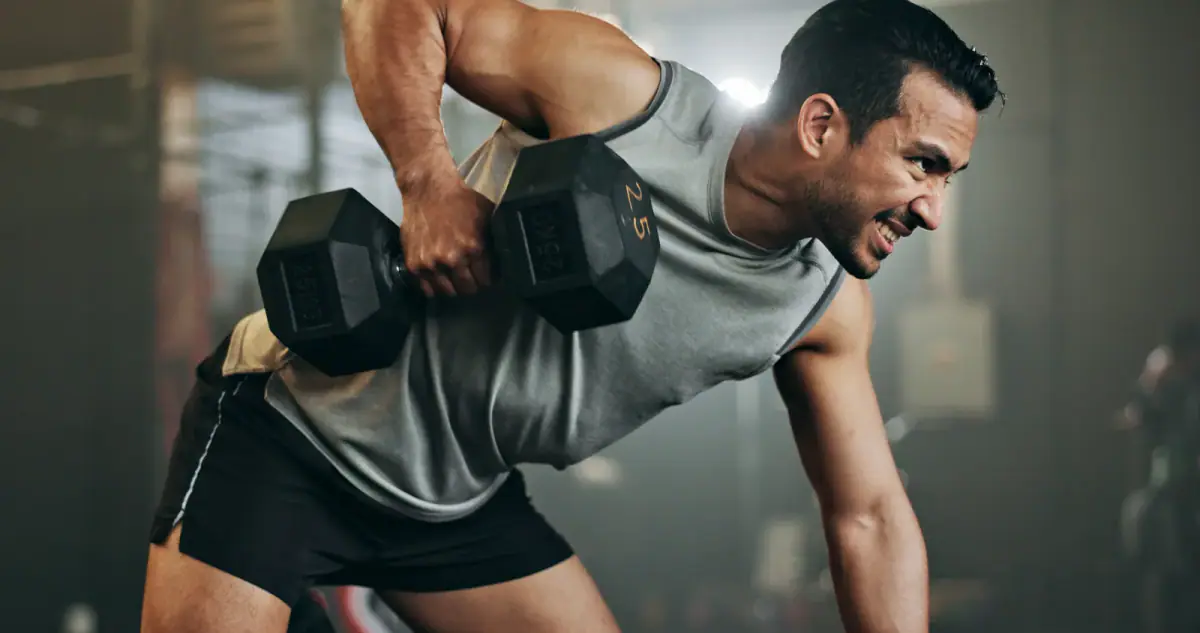 Man doing an arm exercise with a dumbbell on a bench at an indoor gym, a typical day in a push pull legs split