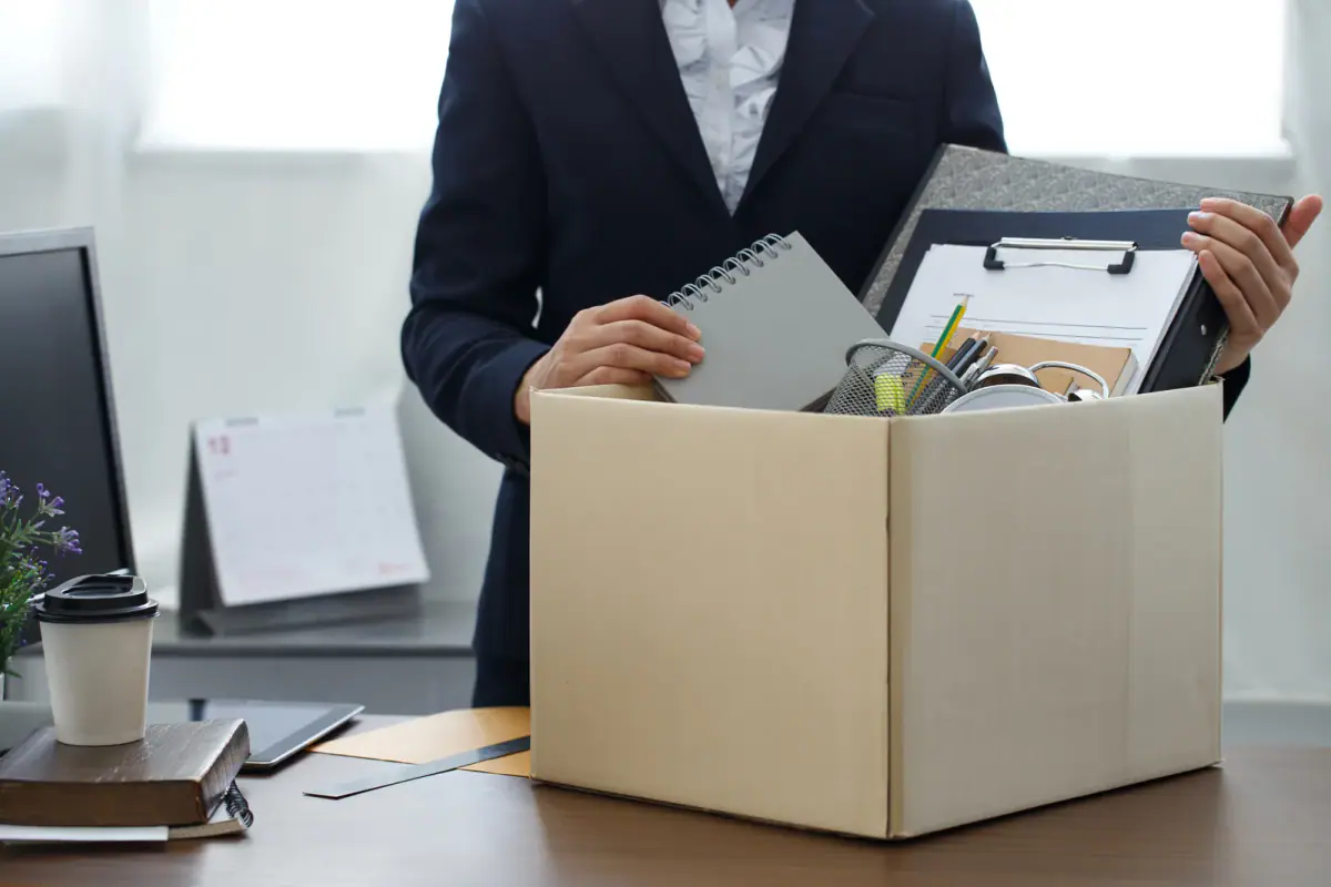 A businesswoman packing her personal belongings as she resigns, like a trainer deciding when to quit a day job