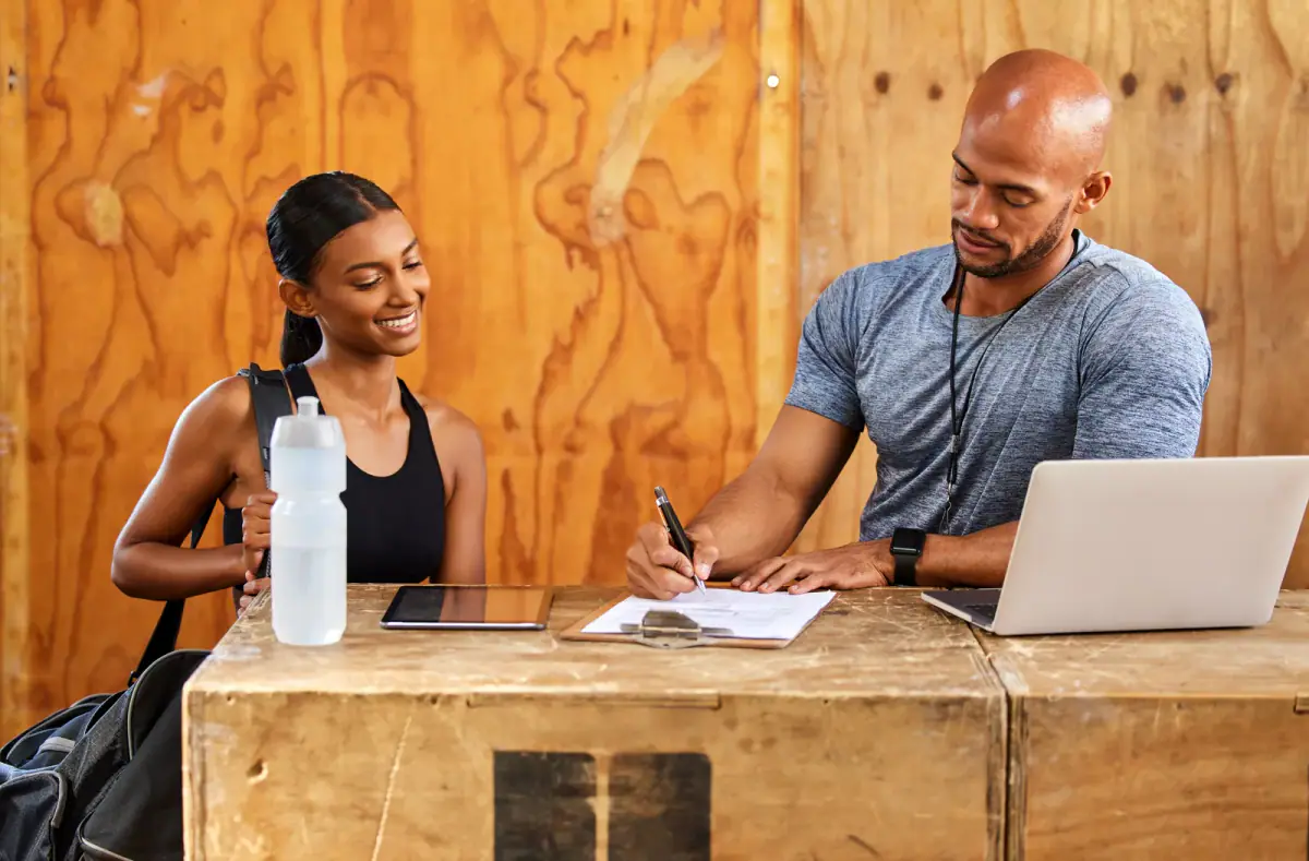Young man and woman reading a document in a gym, the type of agreement to review when renting floor space from a small gym owner