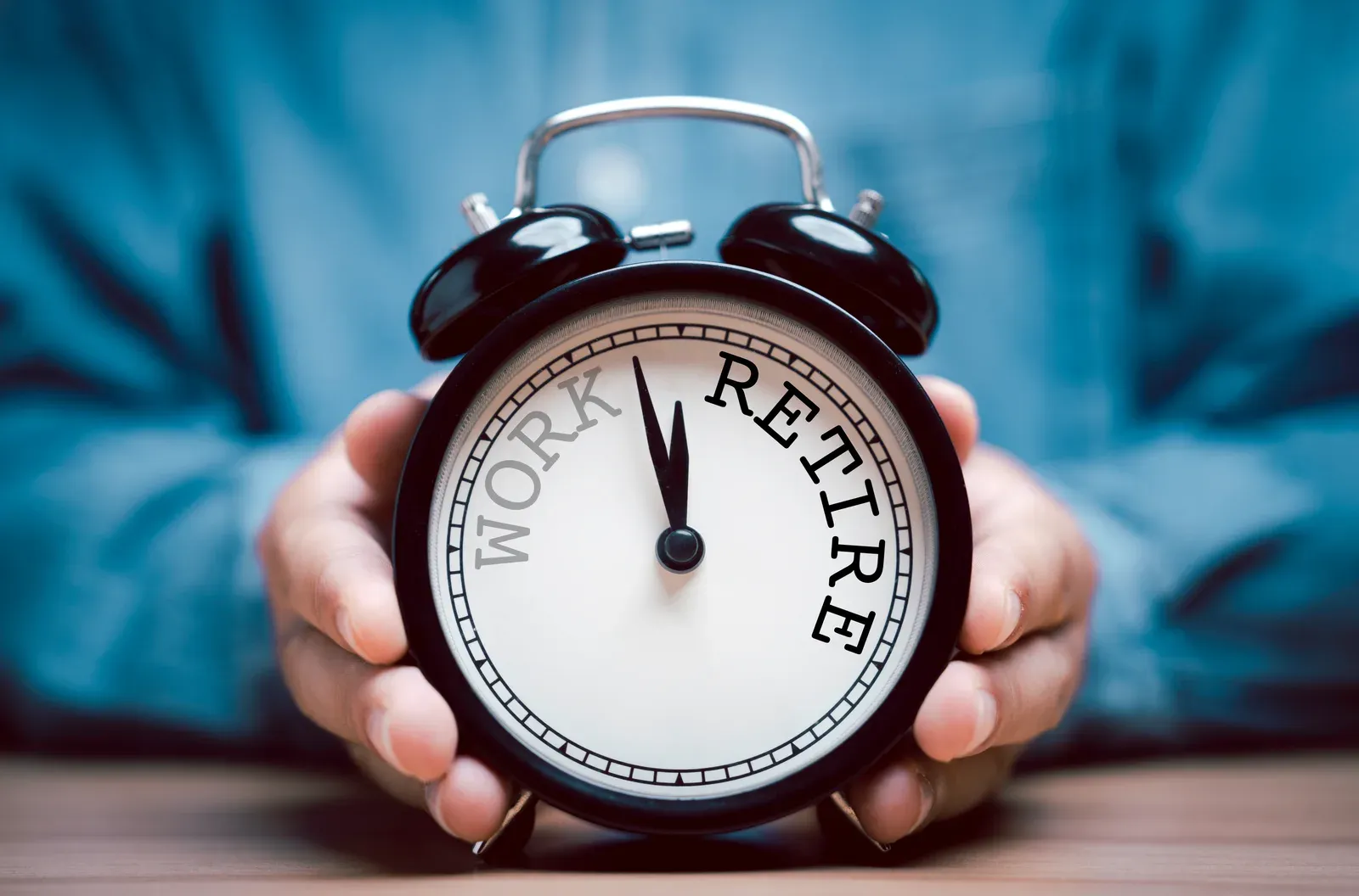 Alarm clock in a businessman's hands, counting down the years to retirement