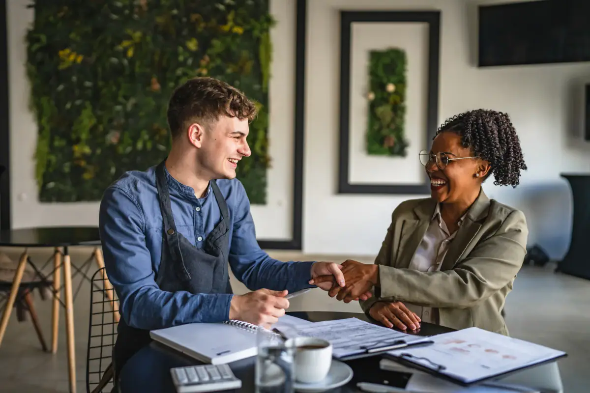 A young male entrepreneur shaking hands with a female financial adviser, like agreeing a revenue split with an associate