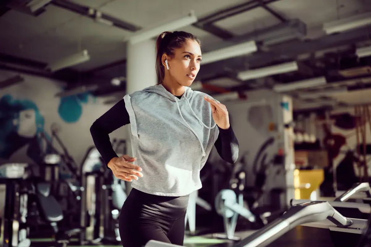 Determined athletic woman running on a treadmill in a gym, the kind of run used in a running gait analysis setup for a PT room