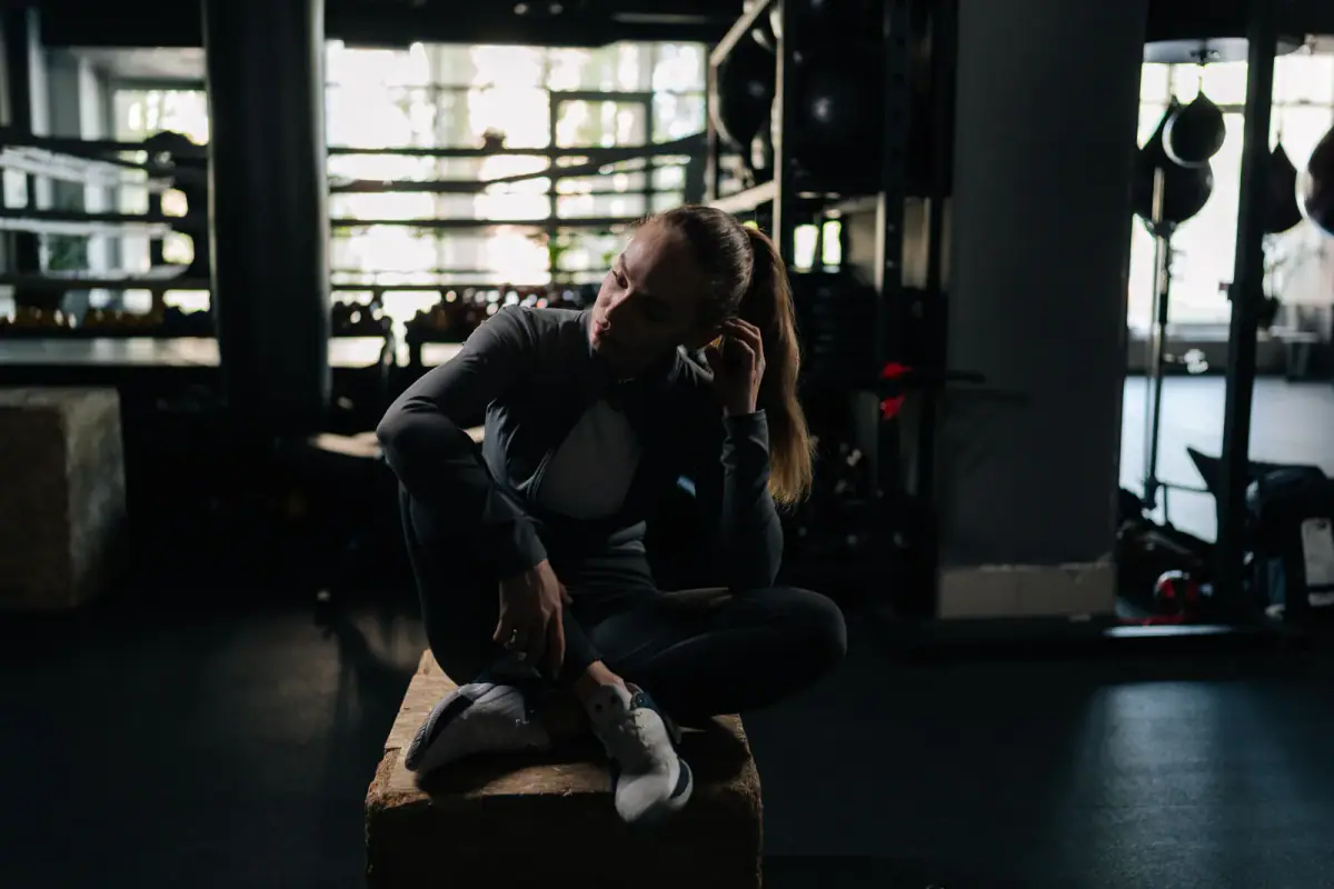 An athletic woman taking a break in a modern fitness club in natural light, relevant to how many sessions a day is too many