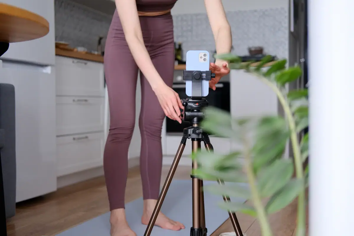 A young woman setting up a phone on a tripod for sports content, relevant to short form video ideas for trainers