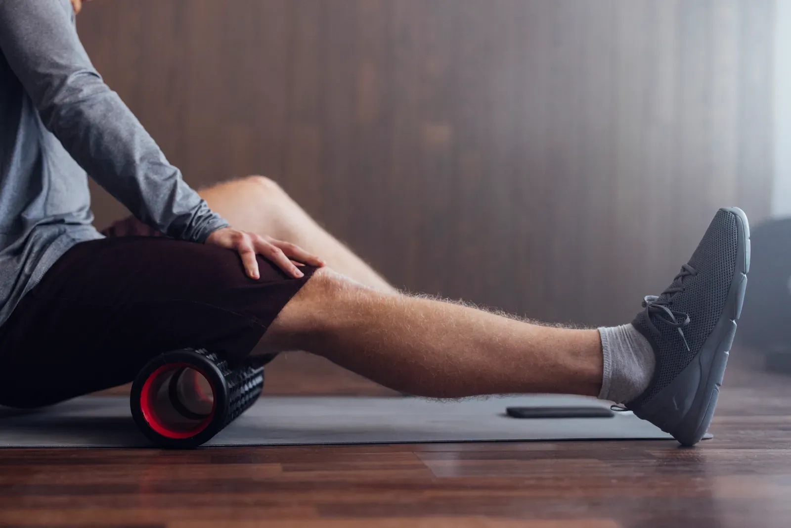 Sportsman rolling out his muscles with a massage roller before an indoor workout