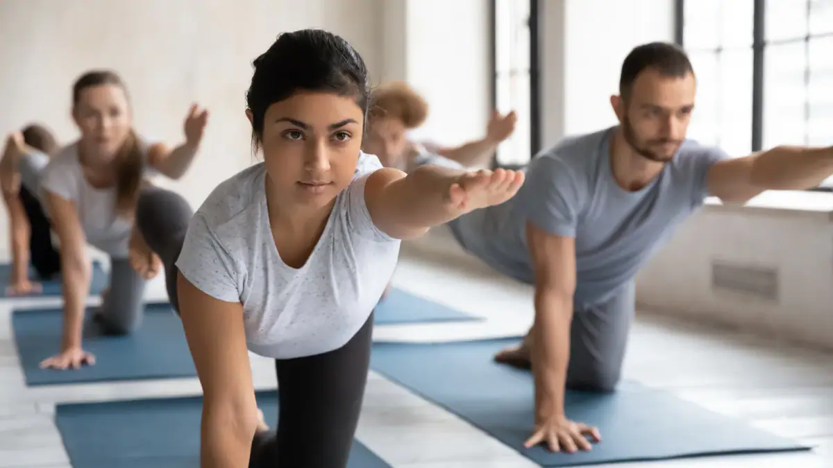 A coach and a group of people doing the Bird Dog pose, relevant to a small group membership monthly fee