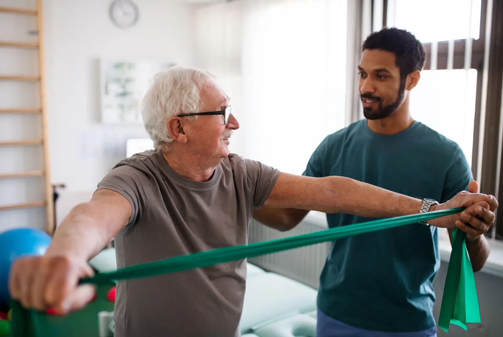 Therapist guiding an older adult through a light resistance exercise