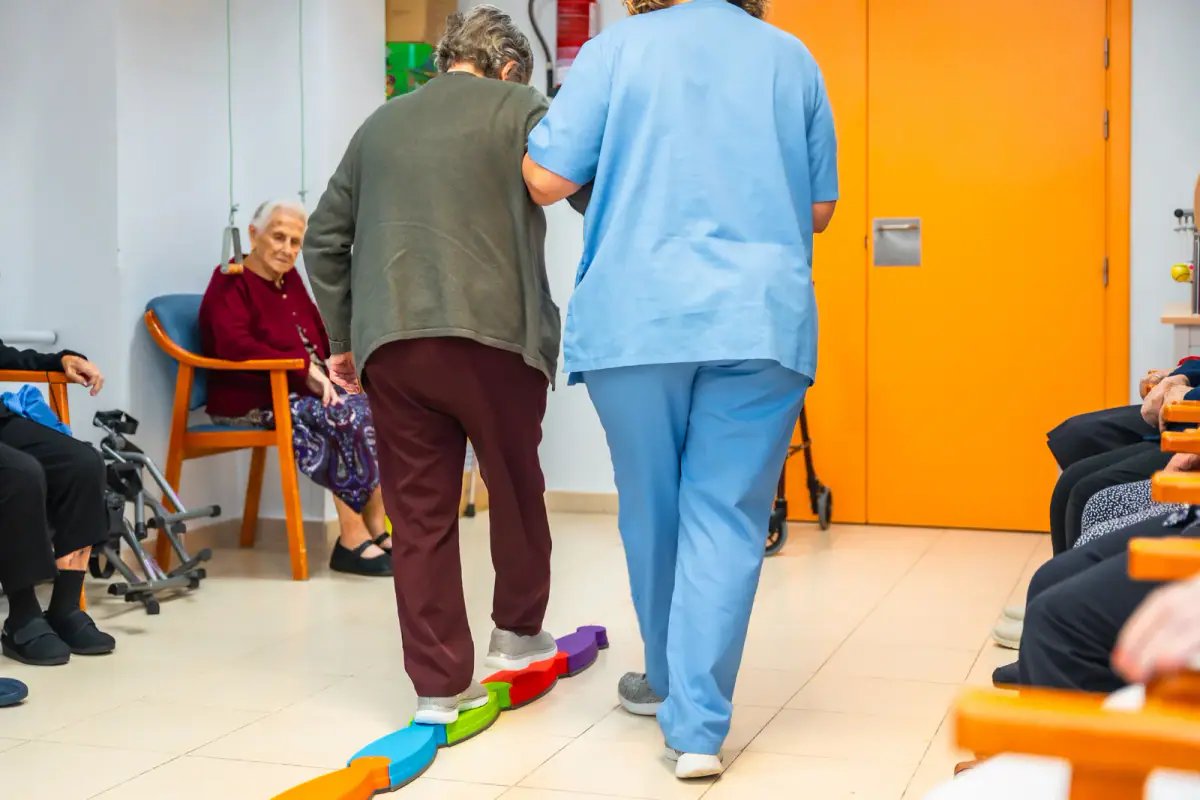 An older woman working on her balance during a physiotherapy session, relevant to space for fall prevention sessions