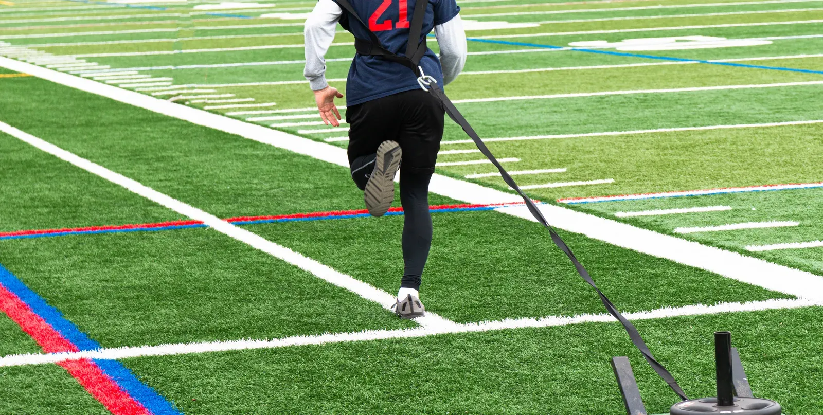Athlete driving forward in a resisted sprint against a harness and band