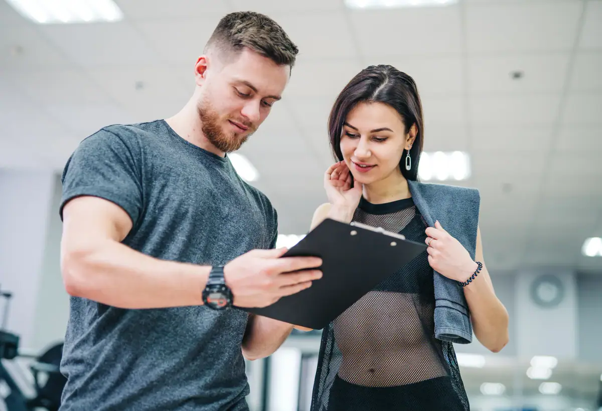 Man and woman resting after a workout and writing in a sports gym, partners who might split a gym lease