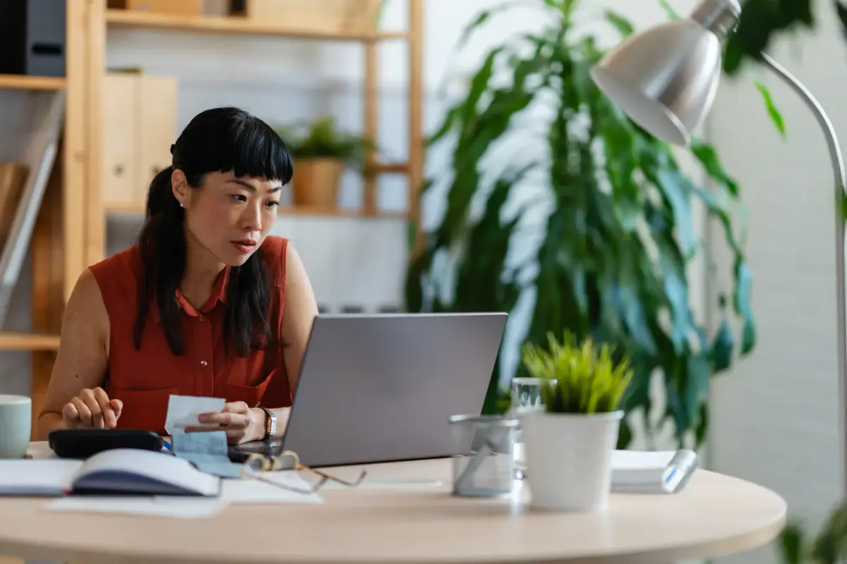 Woman entrepreneur in her home office checking receipts and entering numbers, a start to a personal training business from home