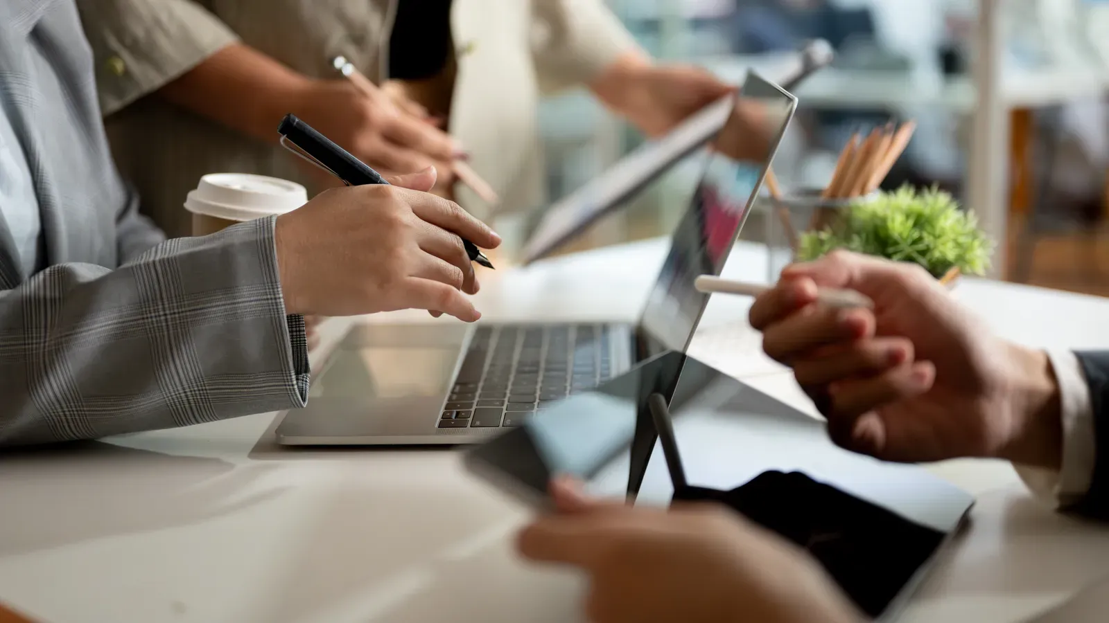 Hands taking notes beside a laptop during a business planning session