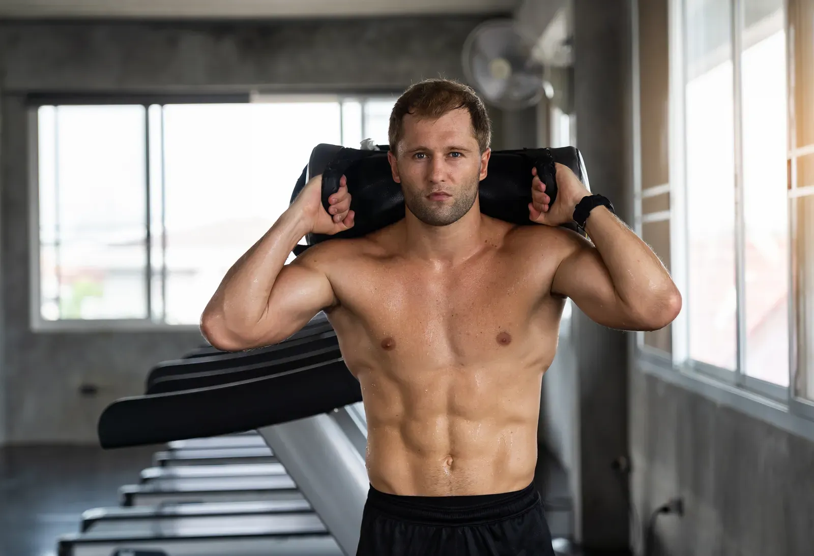 Athlete shouldering a heavy sandbag during a strongman style workout