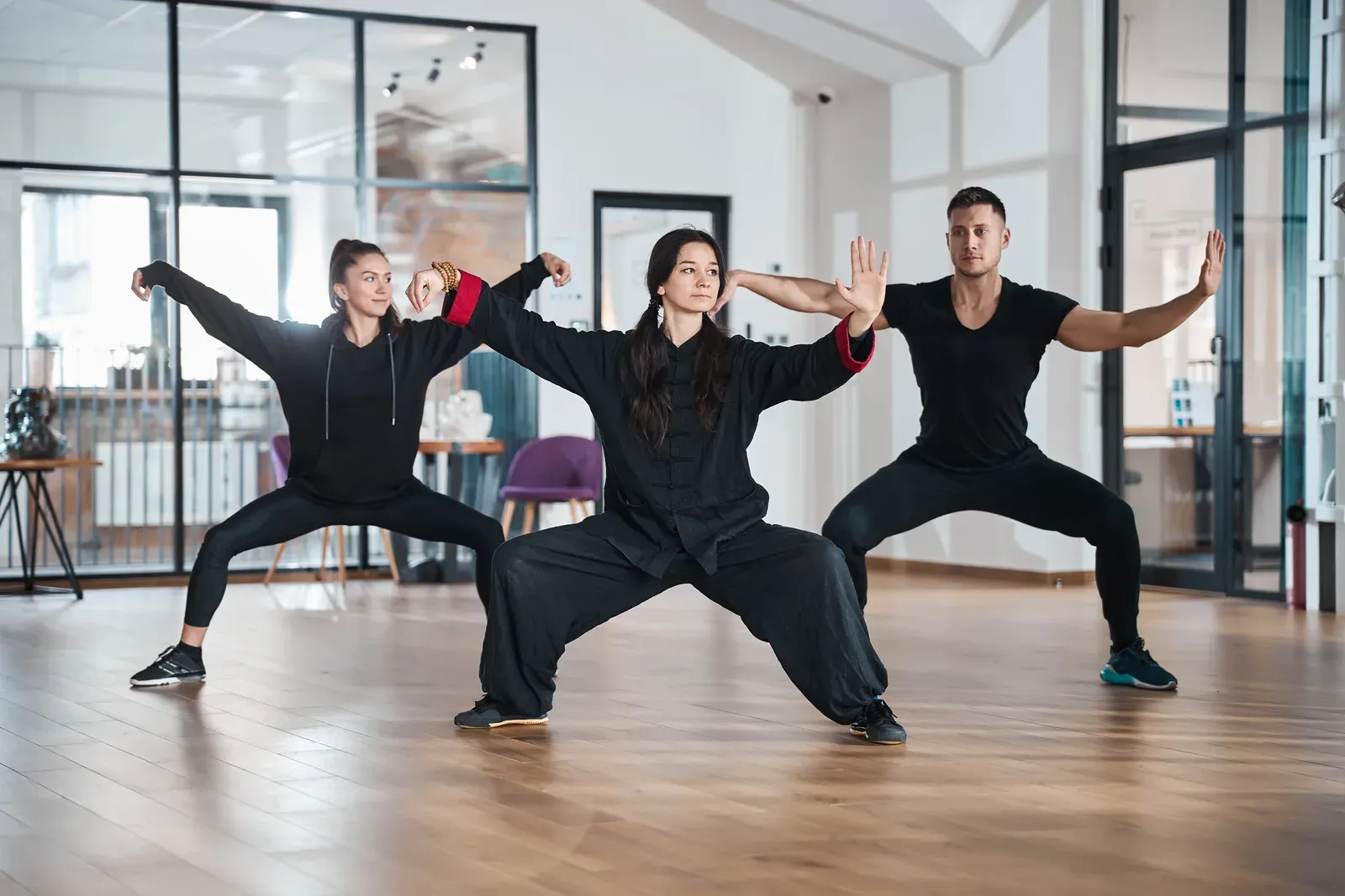 A tai chi teacher leading students through a single whip form
