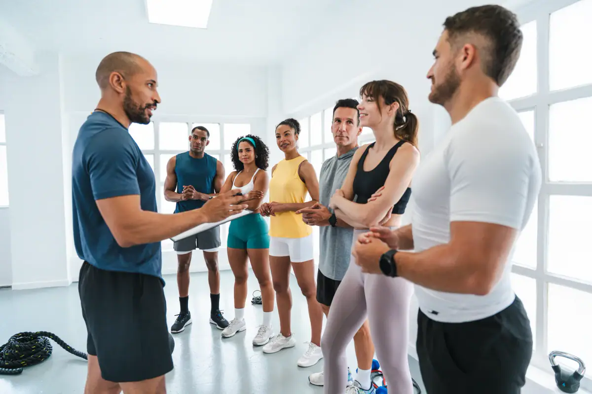 A personal trainer explaining a workout to a group of athletes in a gym, relevant to talking about price in a consultation