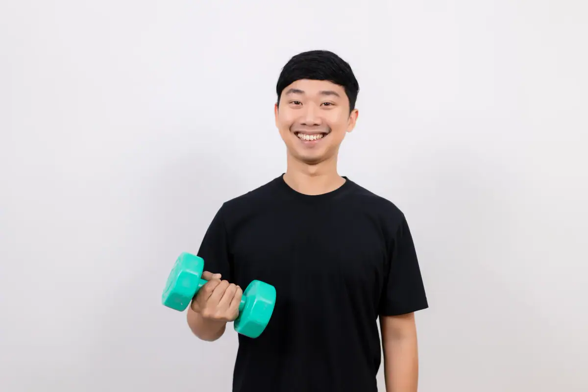 A smiling man holding a dumbbell for exercise, like a client trying out a rented training space