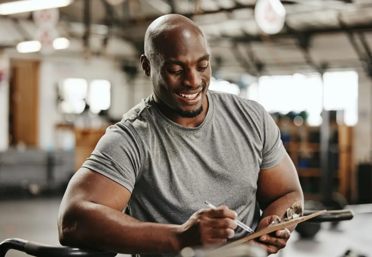 A trainer with a checklist on a clipboard consulting a client in a gym, relevant to tracking prepaid session packs
