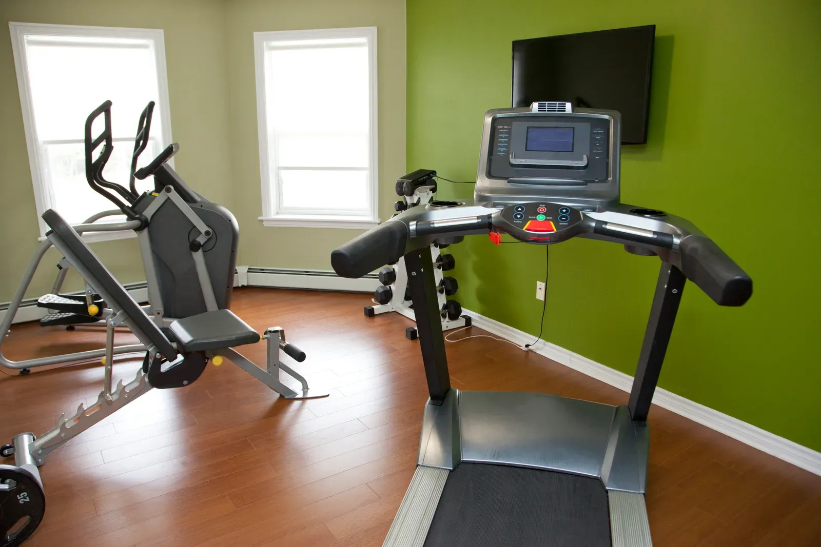 Small apartment building fitness room with a treadmill and dumbbells