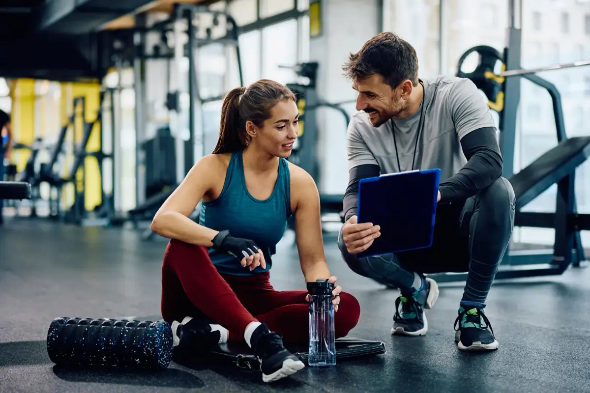 Personal trainer spotting a client on a commercial gym floor