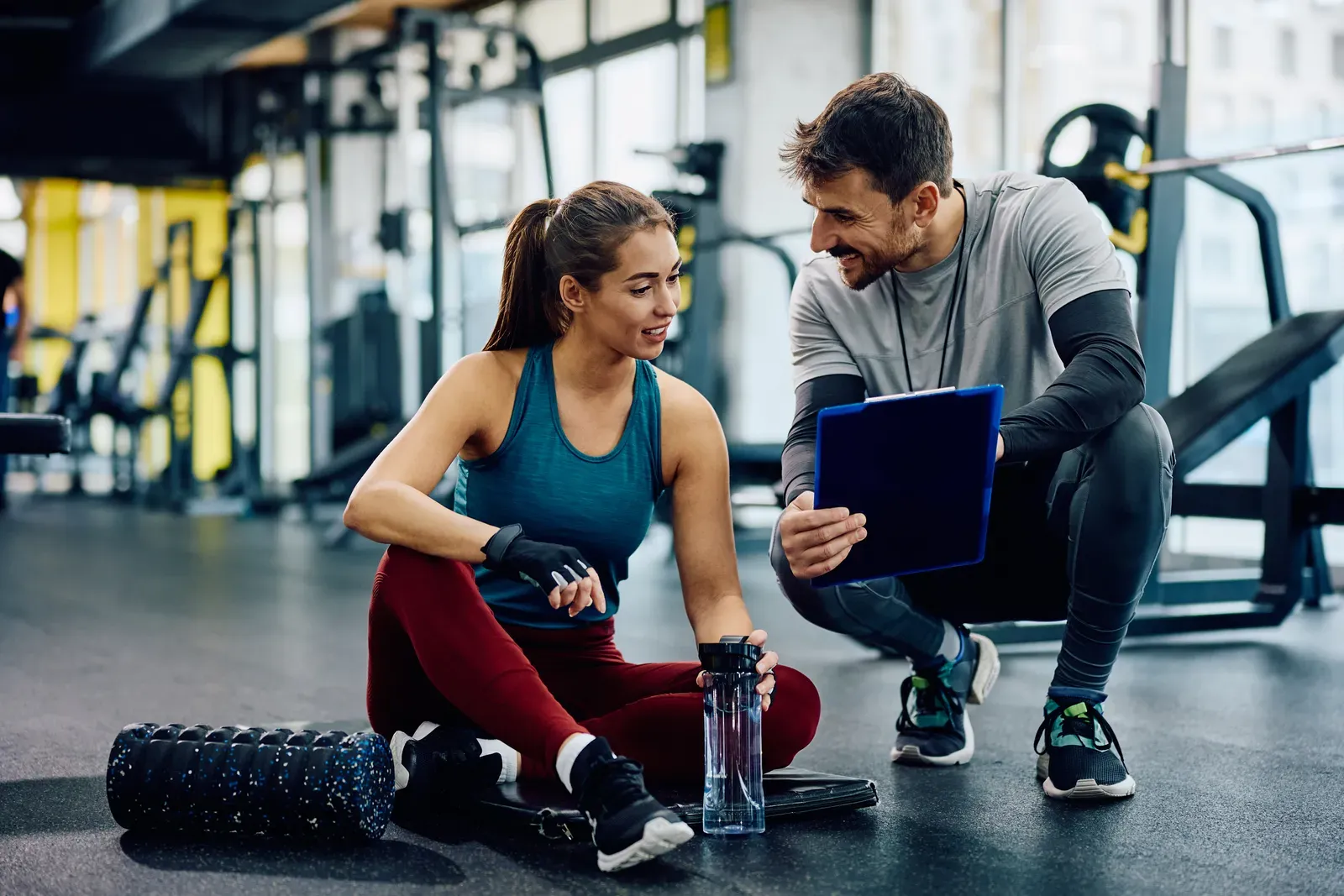 Personal trainer spotting a client on a commercial gym floor