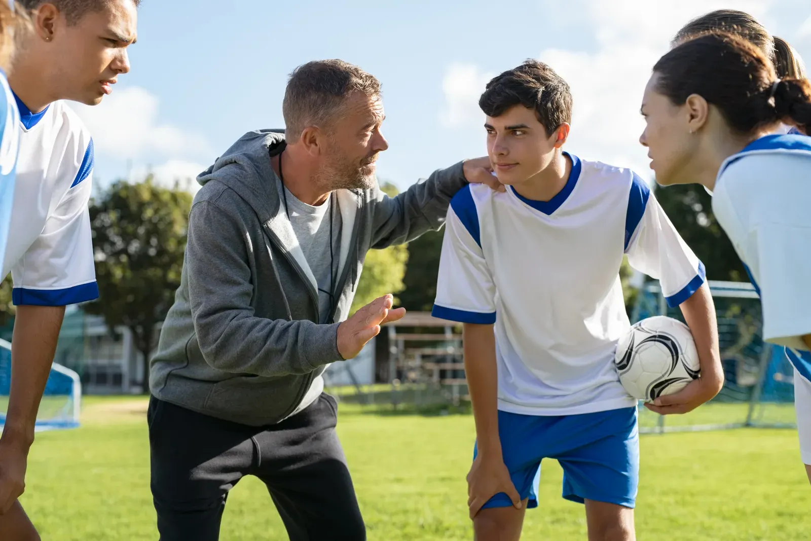 A coach working with a young athlete on a turf training field