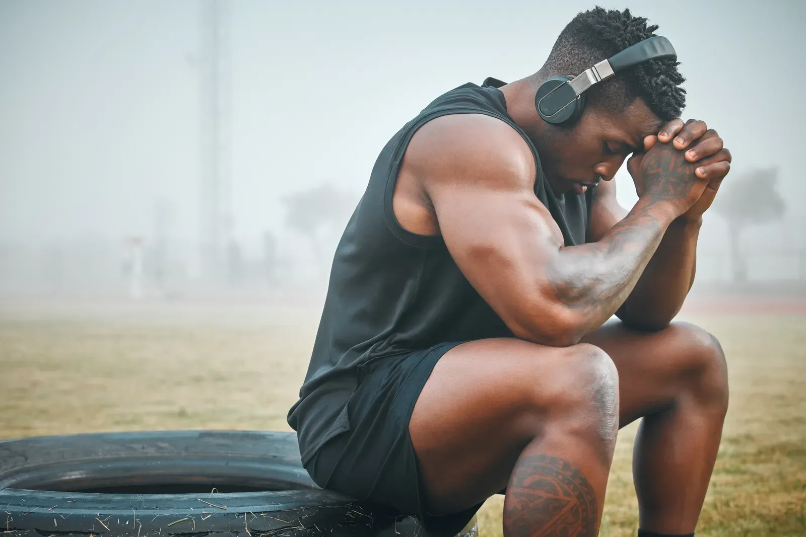 Muscular man wearing headphones while training outdoors on his own time