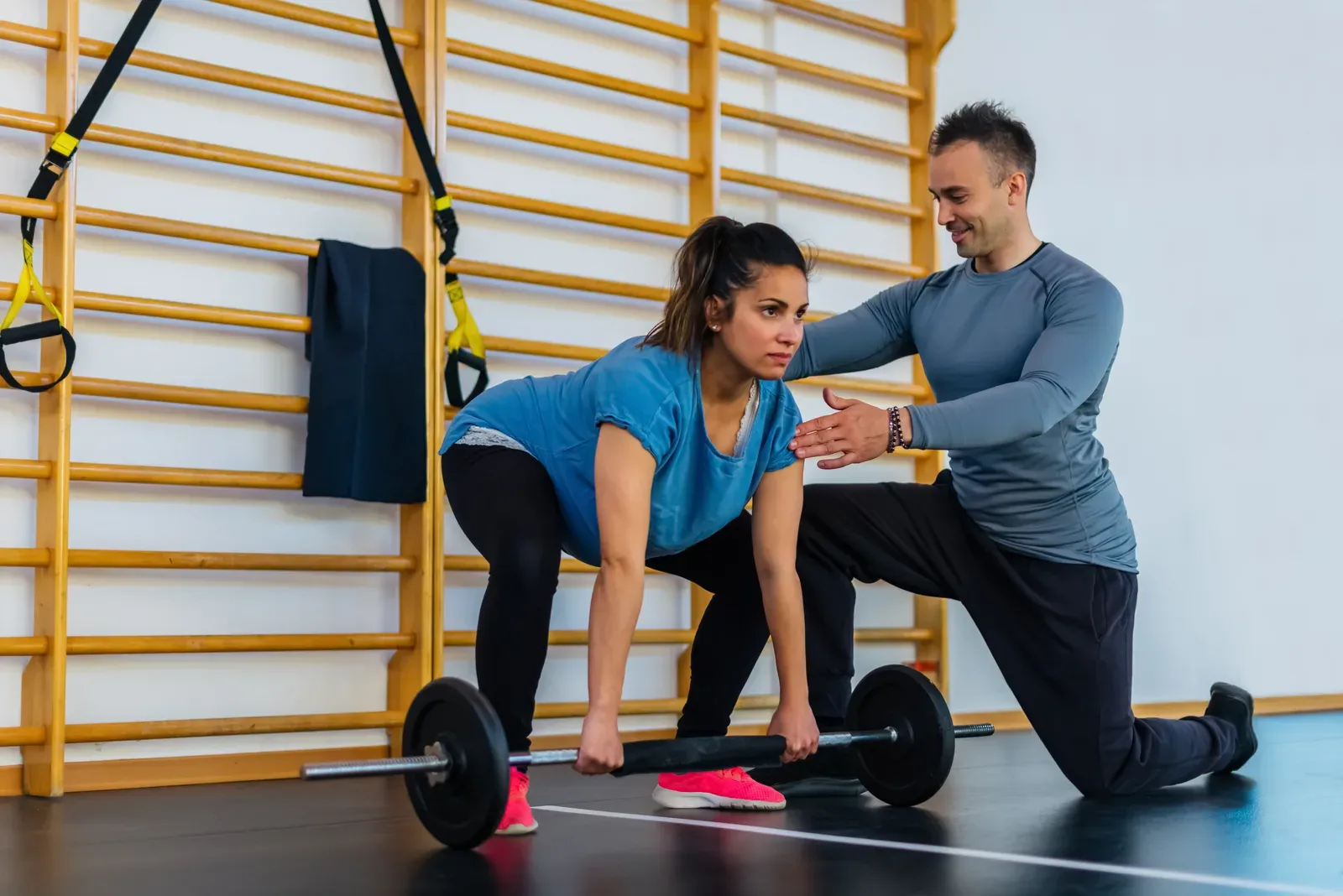 A personal trainer guiding a pregnant client through an indoor workout