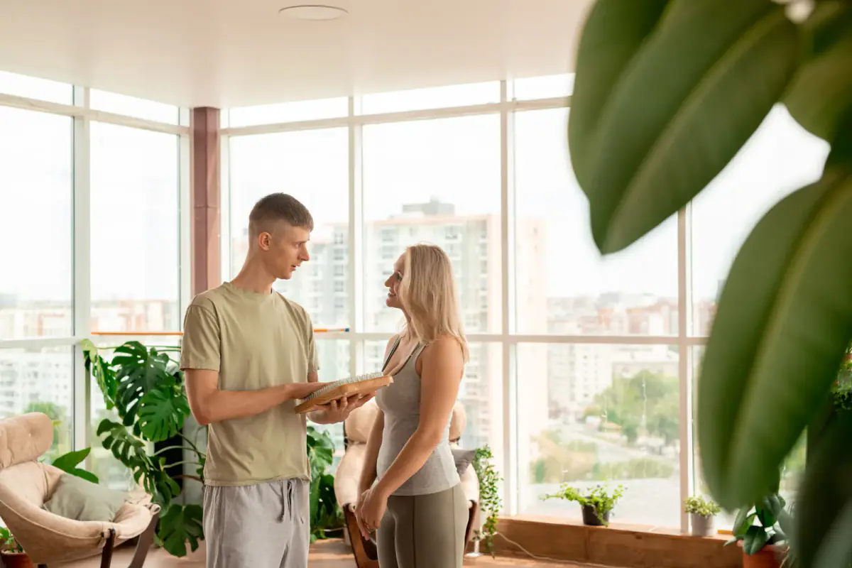 A fit woman in activewear looking at her personal trainer during a consultation, relevant to home visits versus a rented suite