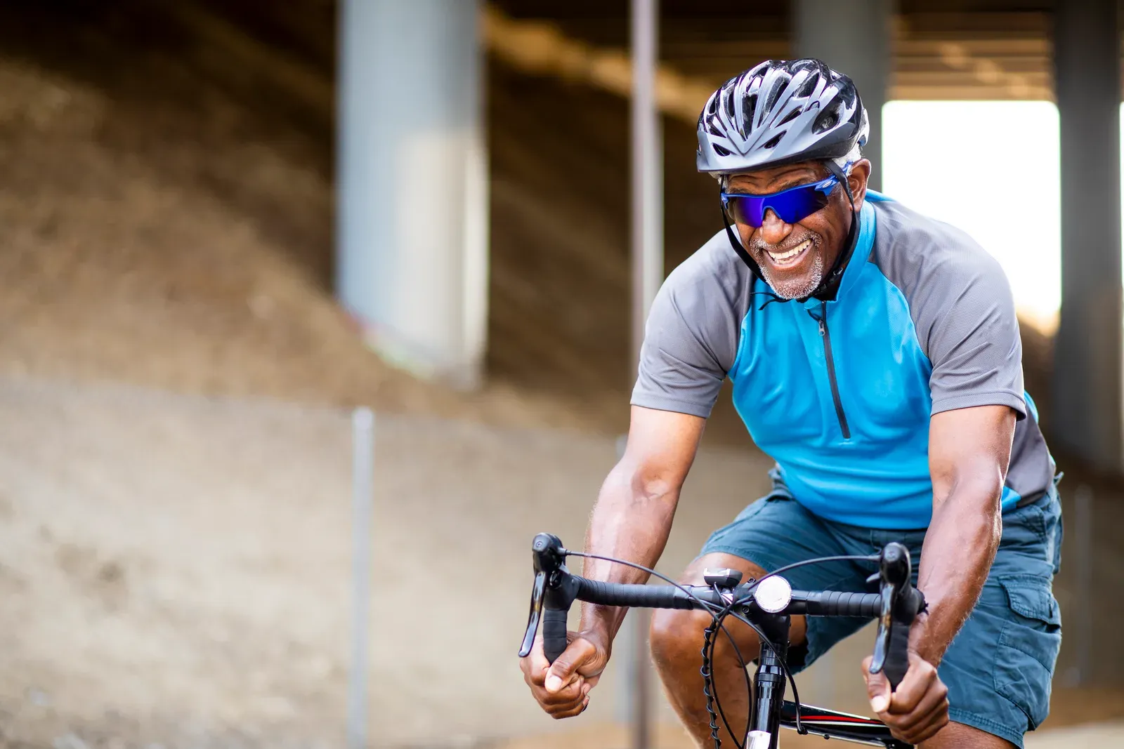 A smiling cyclist in a helmet riding a road bike at an easy pace