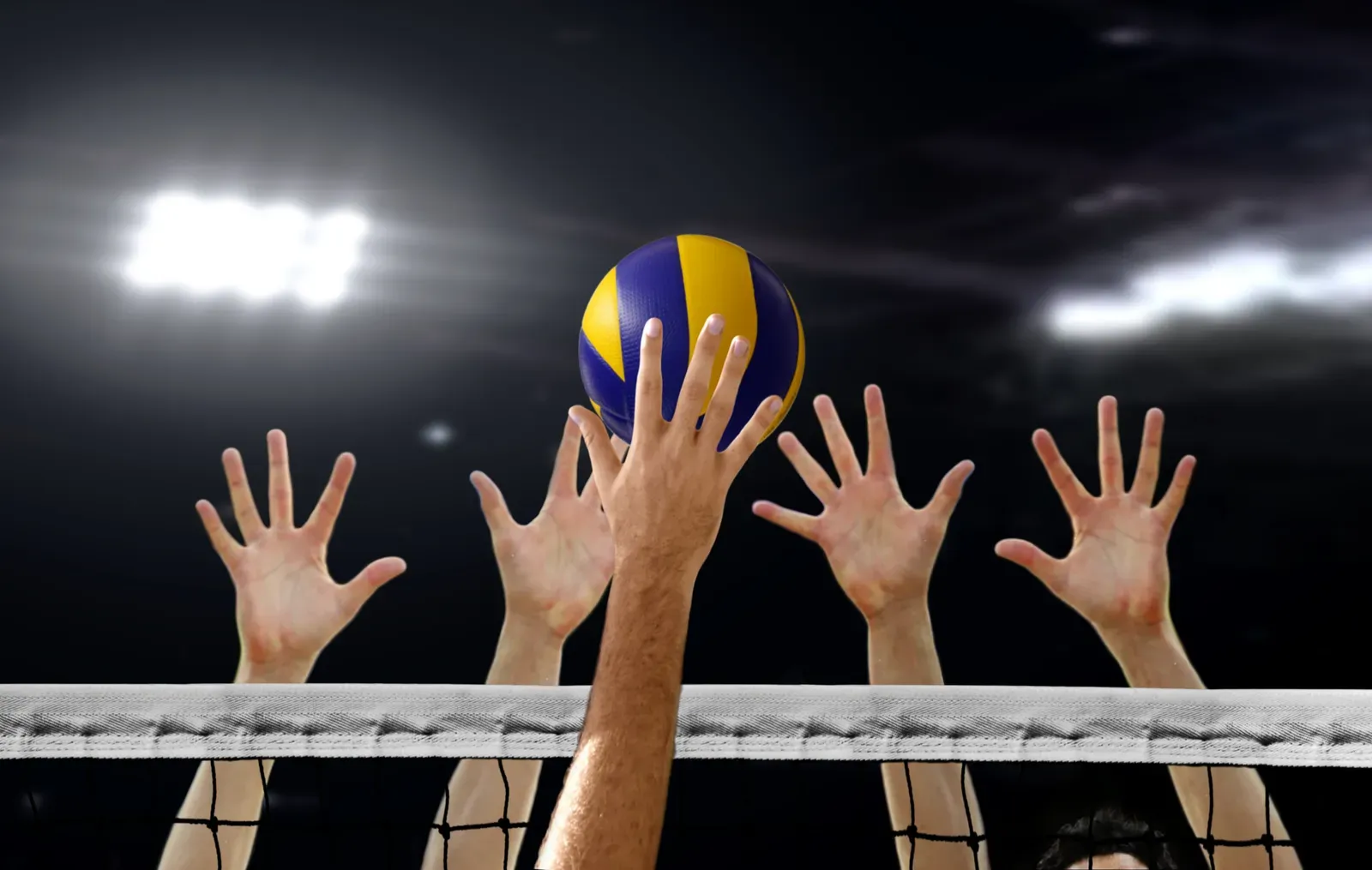 A volleyball player at full extension above the net during a jump