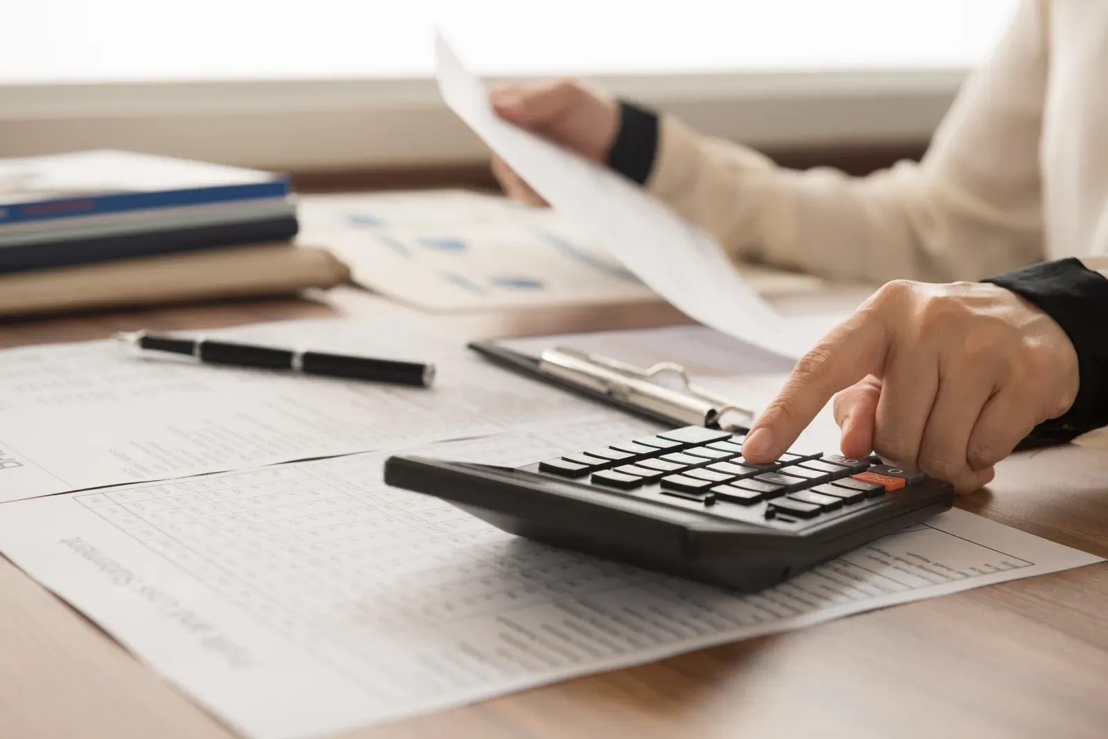 Calculator and paycheck on a desk beside a notebook