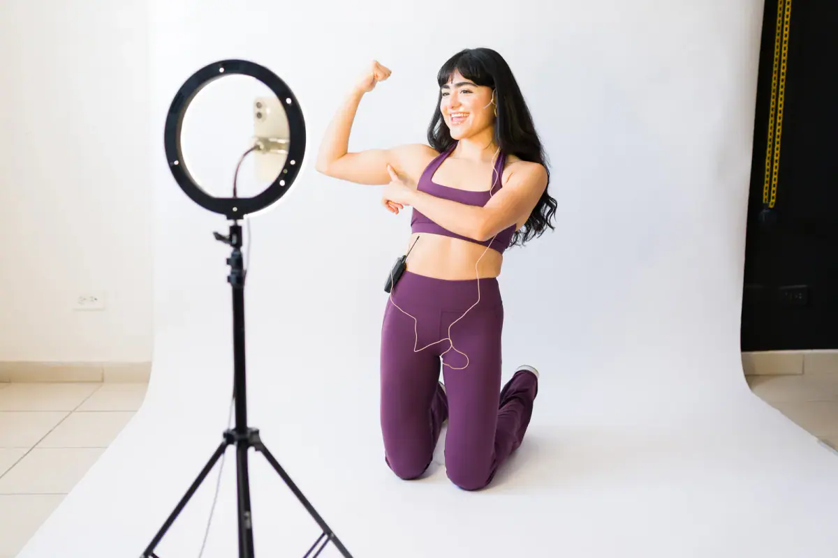 A woman instructor recording a remote fitness class and showing her arm muscles, relevant to filming gym reels