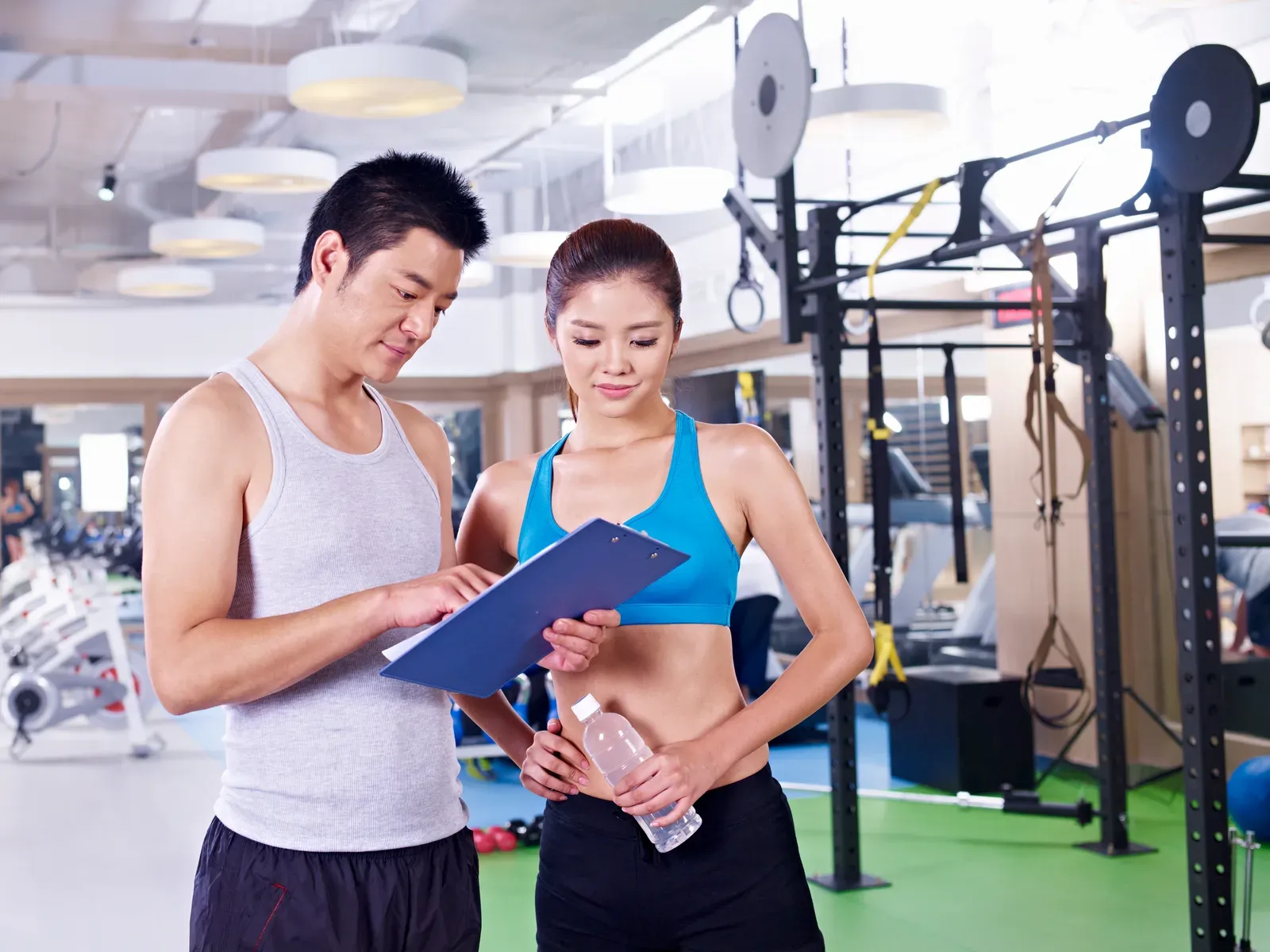 Coach and client checking a printed program together next to gym equipment