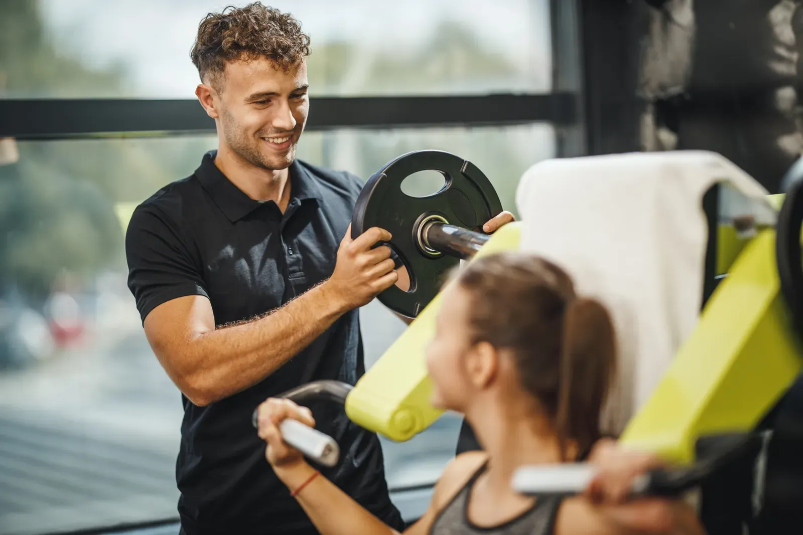 Trainer coaching a client through a dumbbell exercise