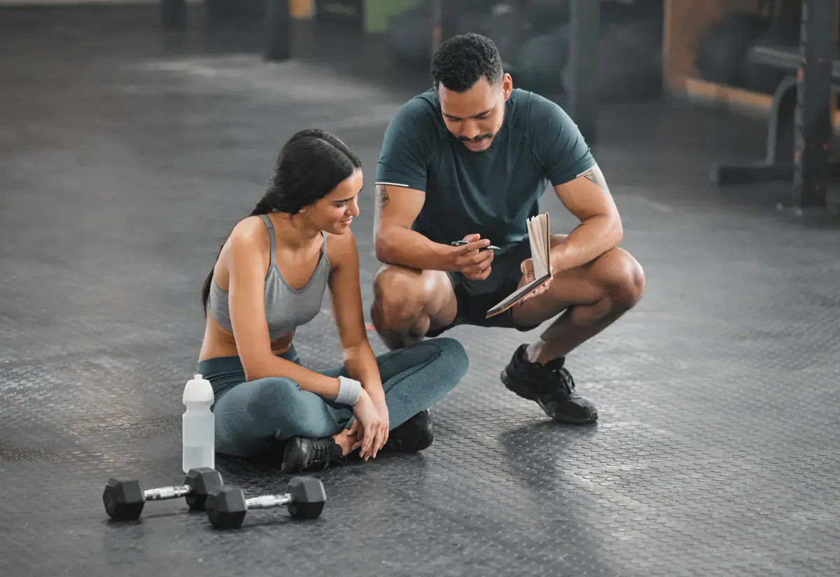 Coach explaining an exercise to a client in a training gym