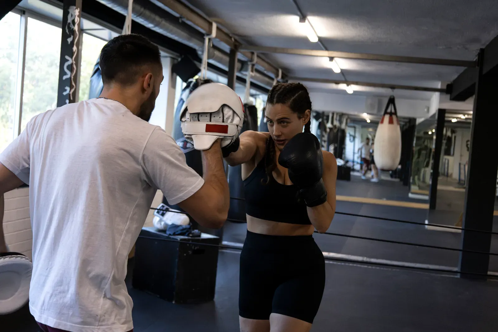 A woman practicing palm strikes on pads held by an instructor