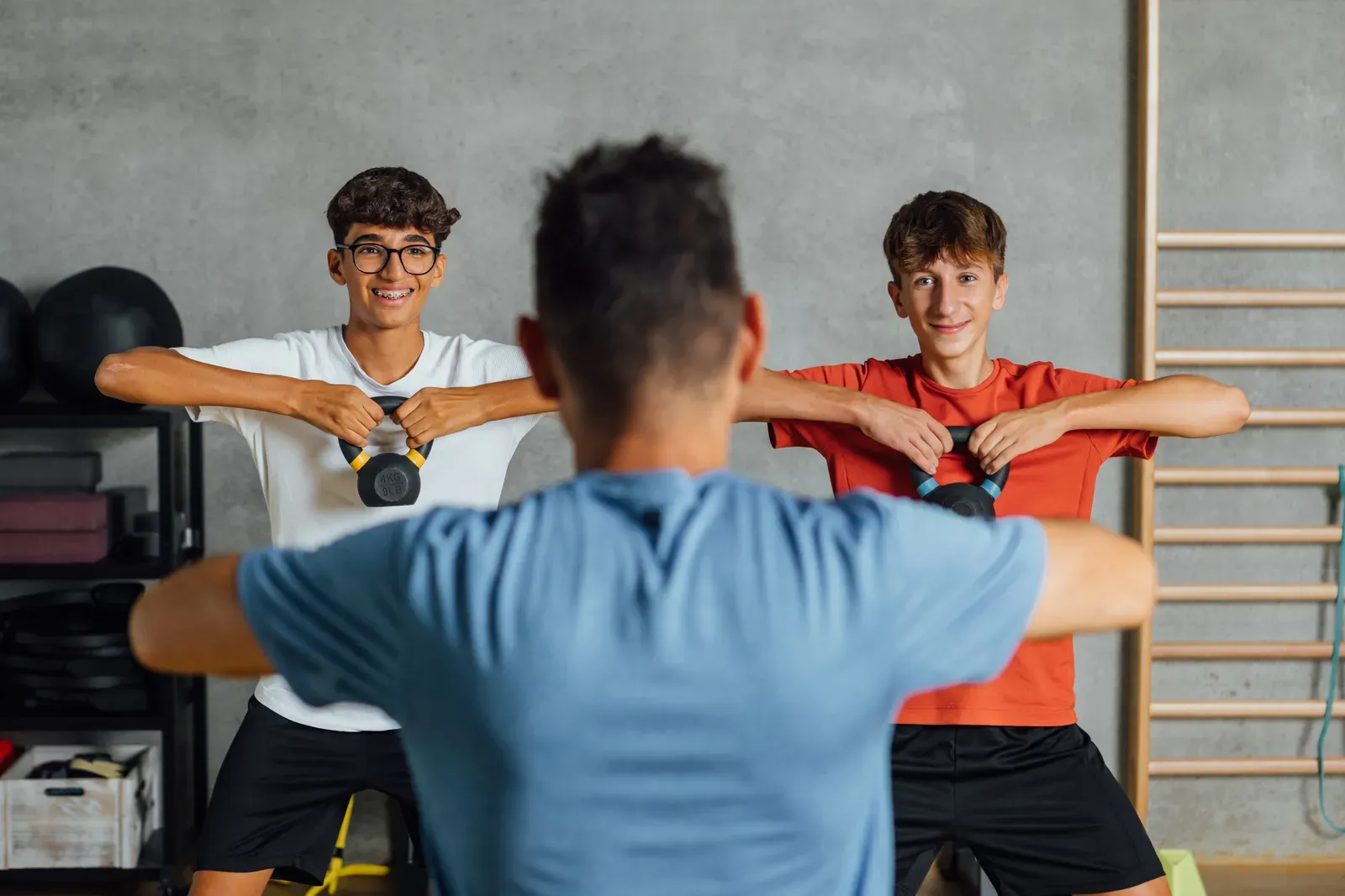 A coach guiding a young athlete through a training drill indoors